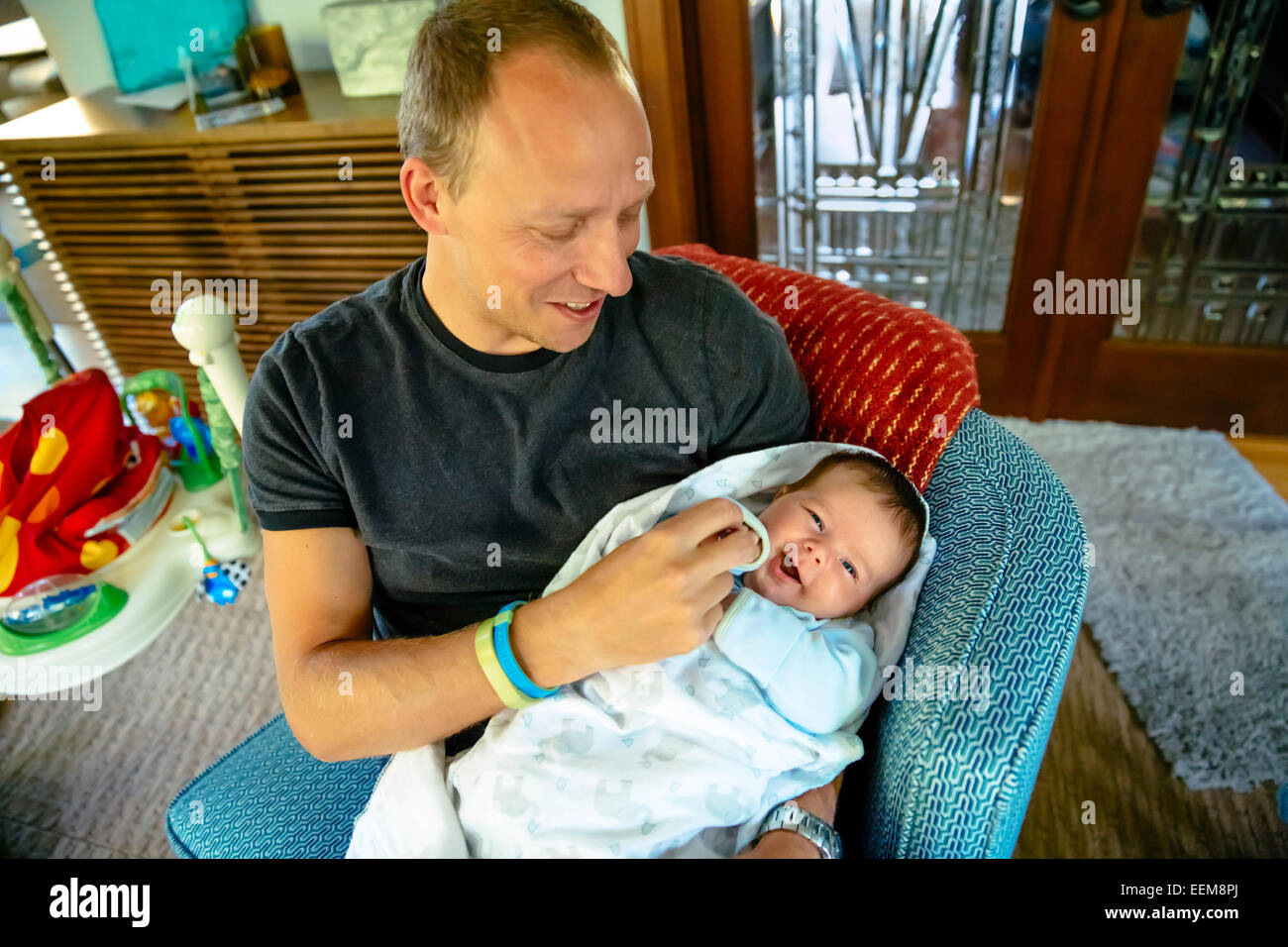 Caucasian father holding baby boy in armchair Stock Photo Alamy