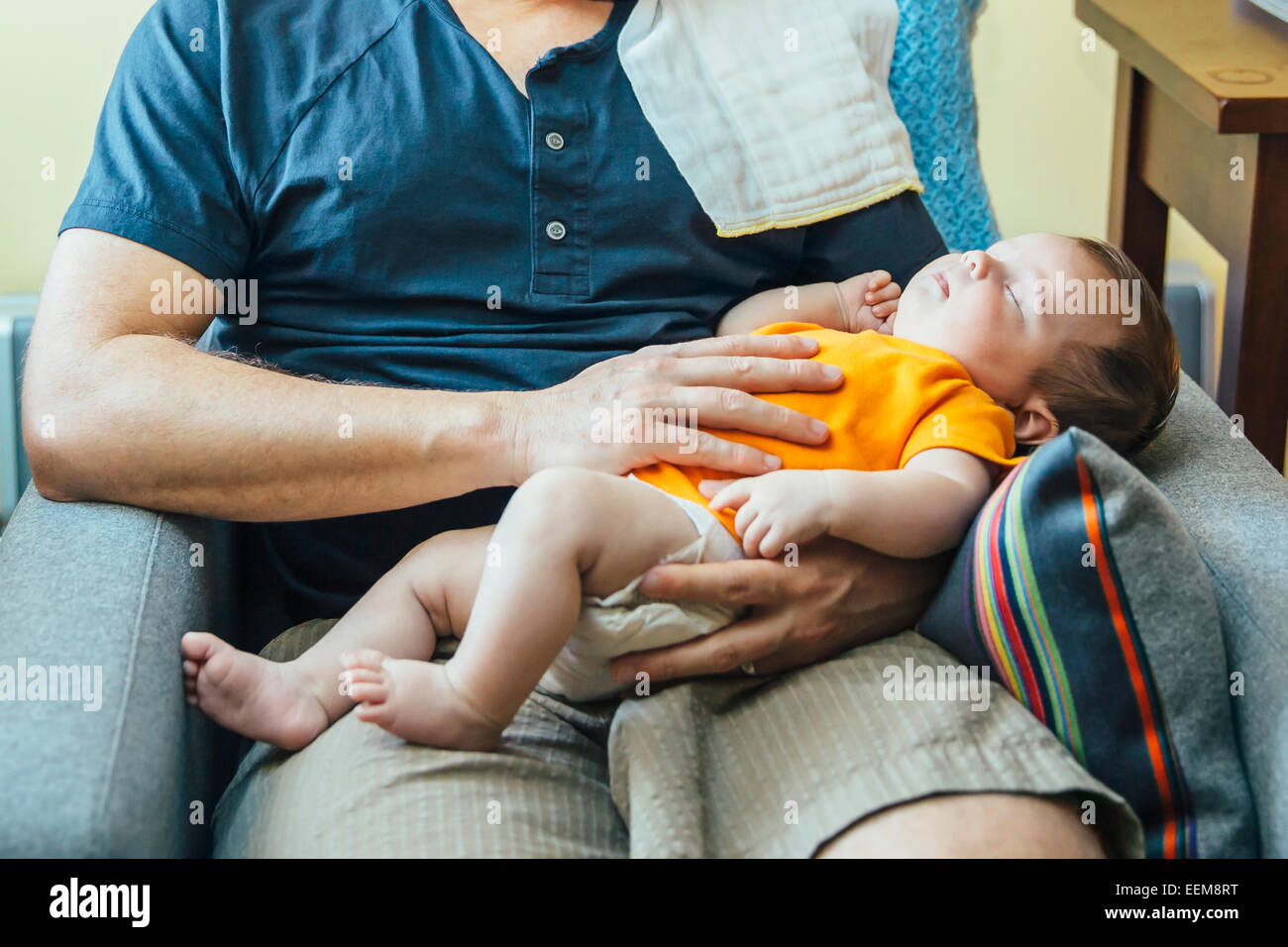Caucasian father holding sleeping baby boy in armchair Stock Photo Alamy