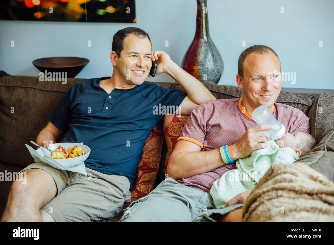 Caucasian gay couple relaxing with baby boy on sofa Stock Photo