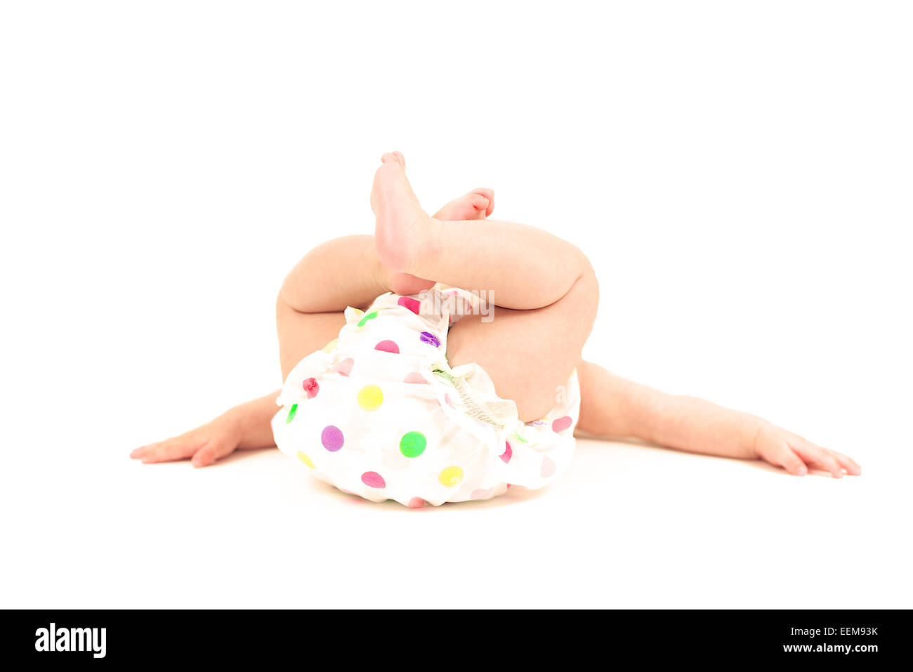 Baby girl lying on floor in spotty nappy pants Stock Photo
