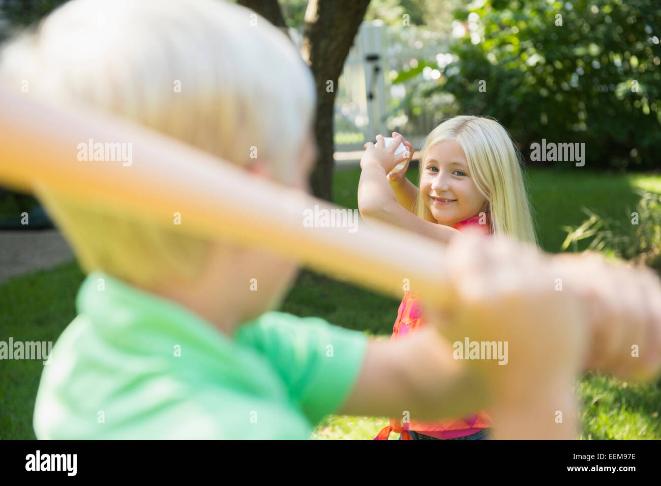 Caucasian children playing baseball in backyard Stock Photo
