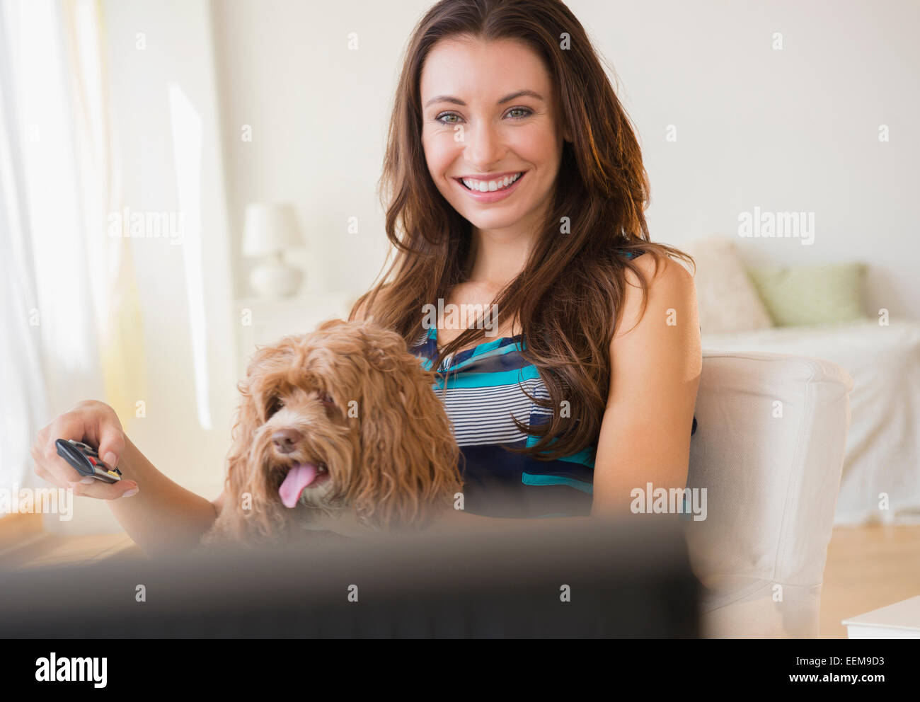 Caucasian woman watching television with pet dog Stock Photo