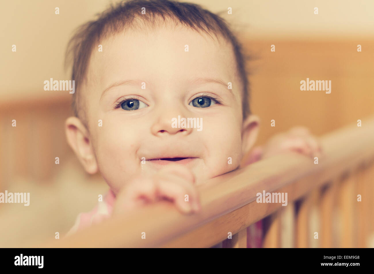 Baby girl (6-11 months) looking over her crib Stock Photo