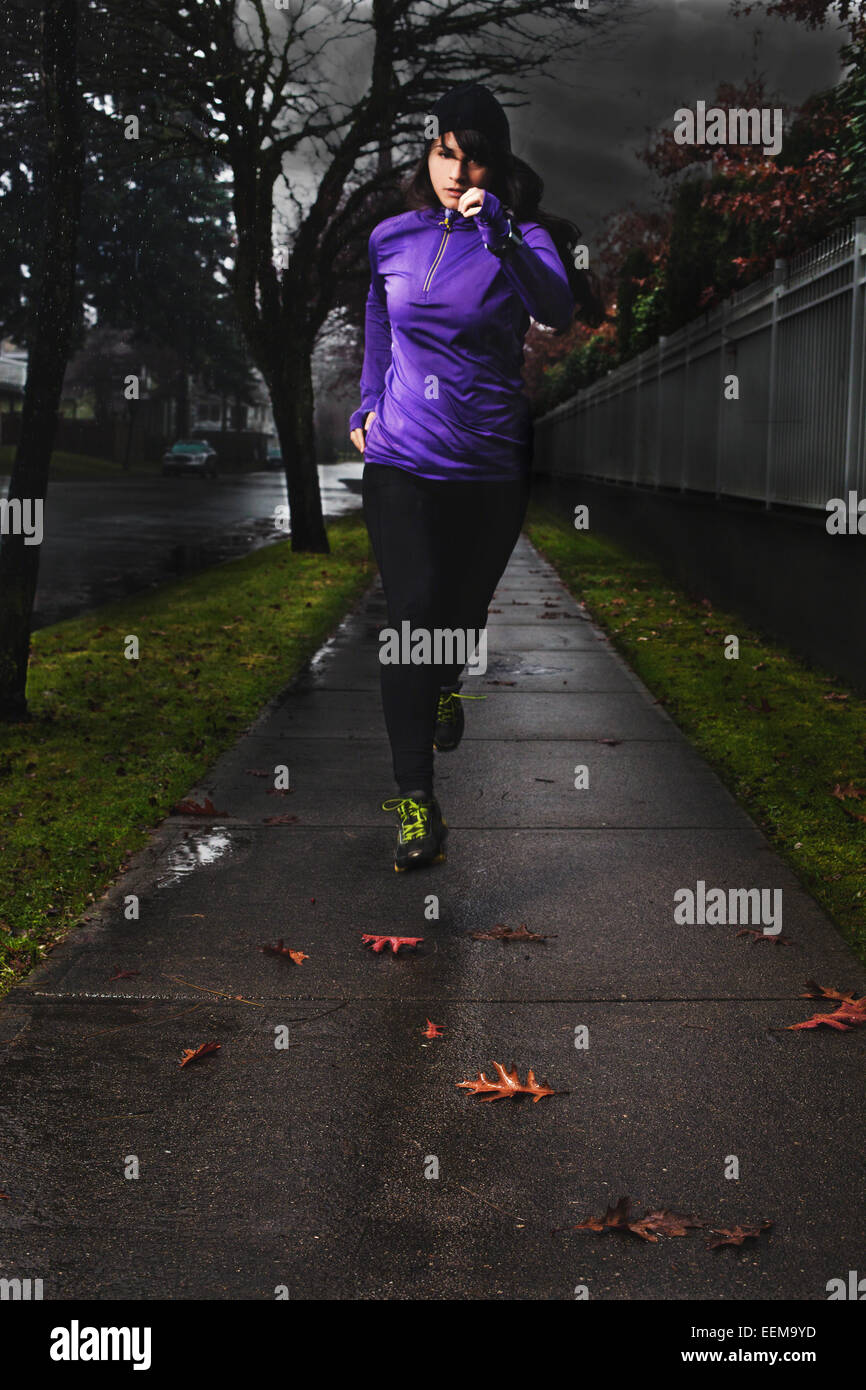 Woman jogging in the city in the rain Stock Photo