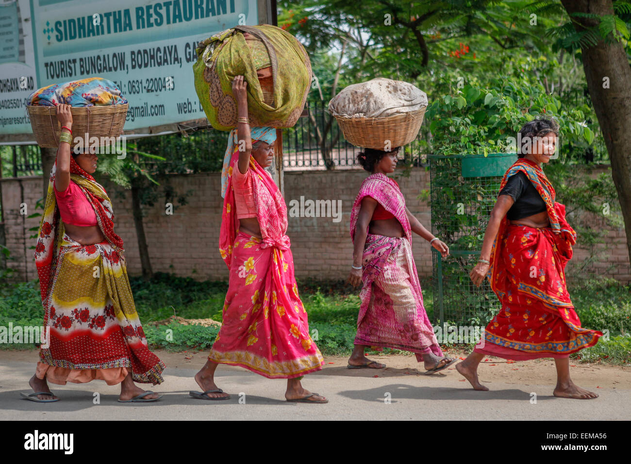Women carry things on their heads as they are walking on the main avenue in Bodh Gaya, Bihar, India. Stock Photo