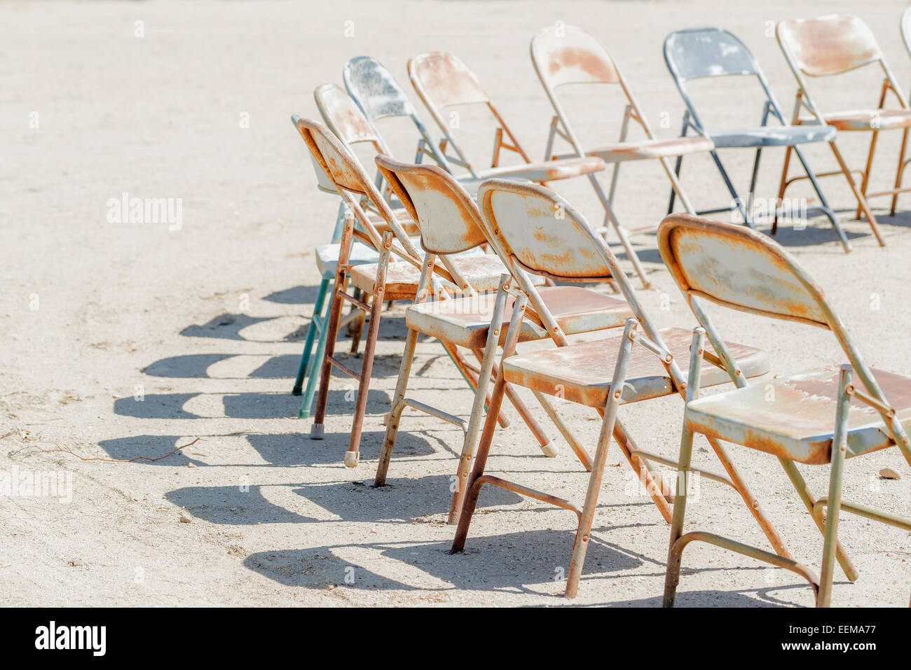 Dilapidated chairs arranged in circle in dirt field Stock Photo