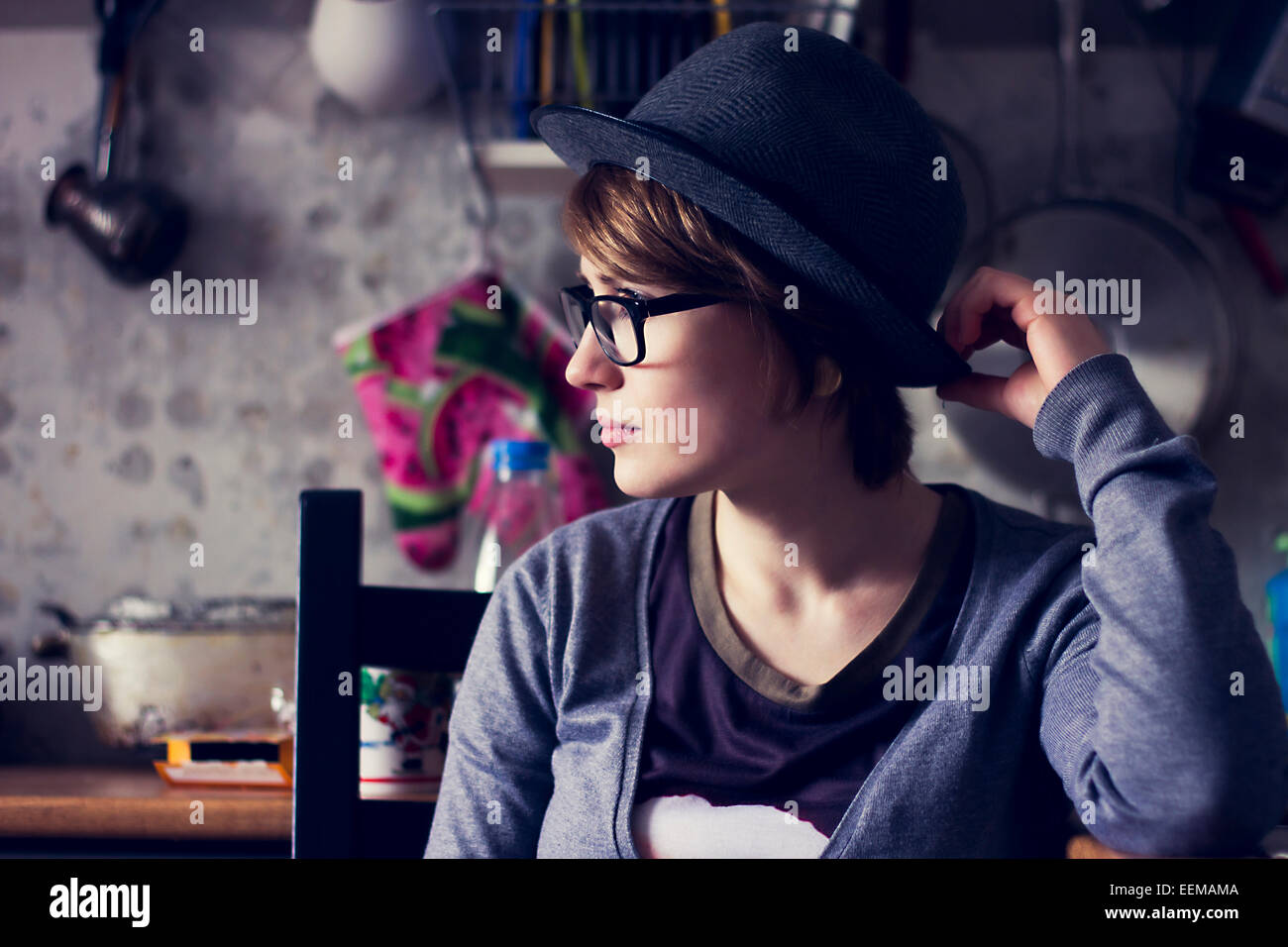 Caucasian woman wearing hat and eyeglasses in kitchen Stock Photo