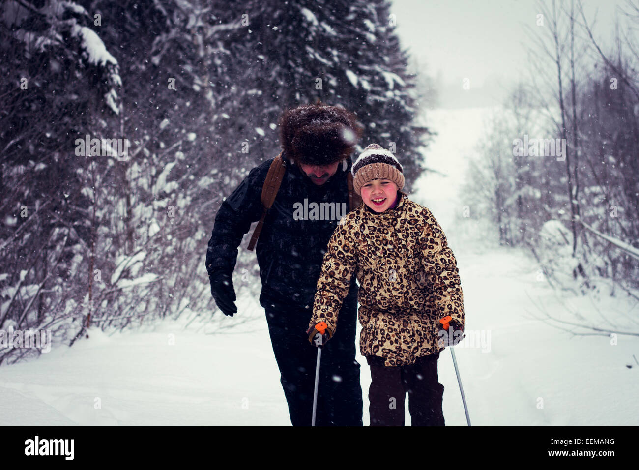 Caucasian father and daughter cross-country skiing on snowy road Stock Photo