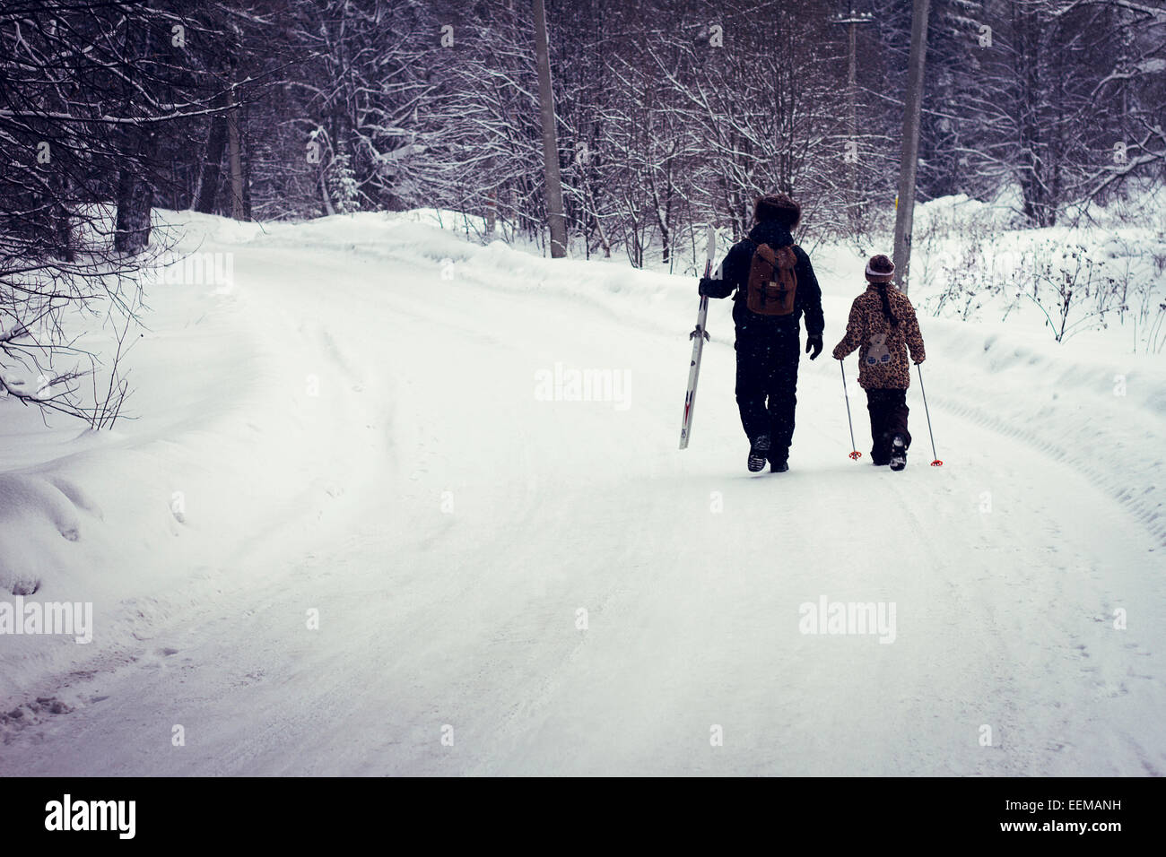 Caucasian father and daughter cross-country skiing on snowy road Stock Photo