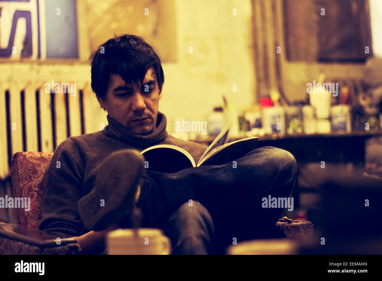 Asian man reading in armchair Stock Photo