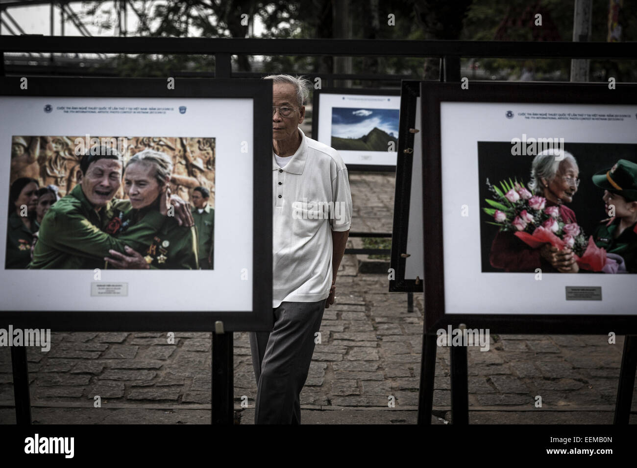 An old man visits a press photo exhibition with images of tributes from the Vietnamese government to war veterans. Stock Photo