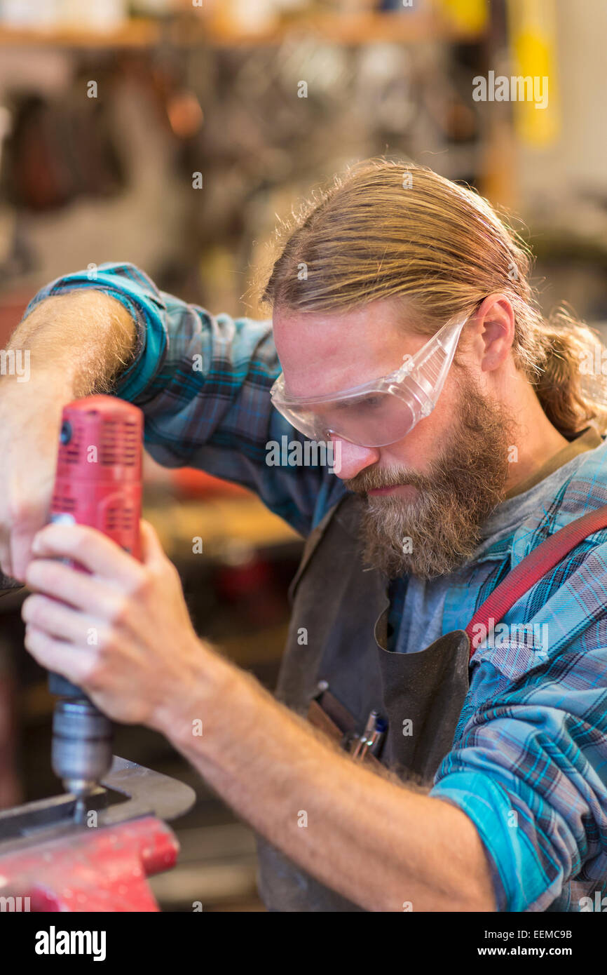 Caucasian craftsman drilling in workshop Stock Photo