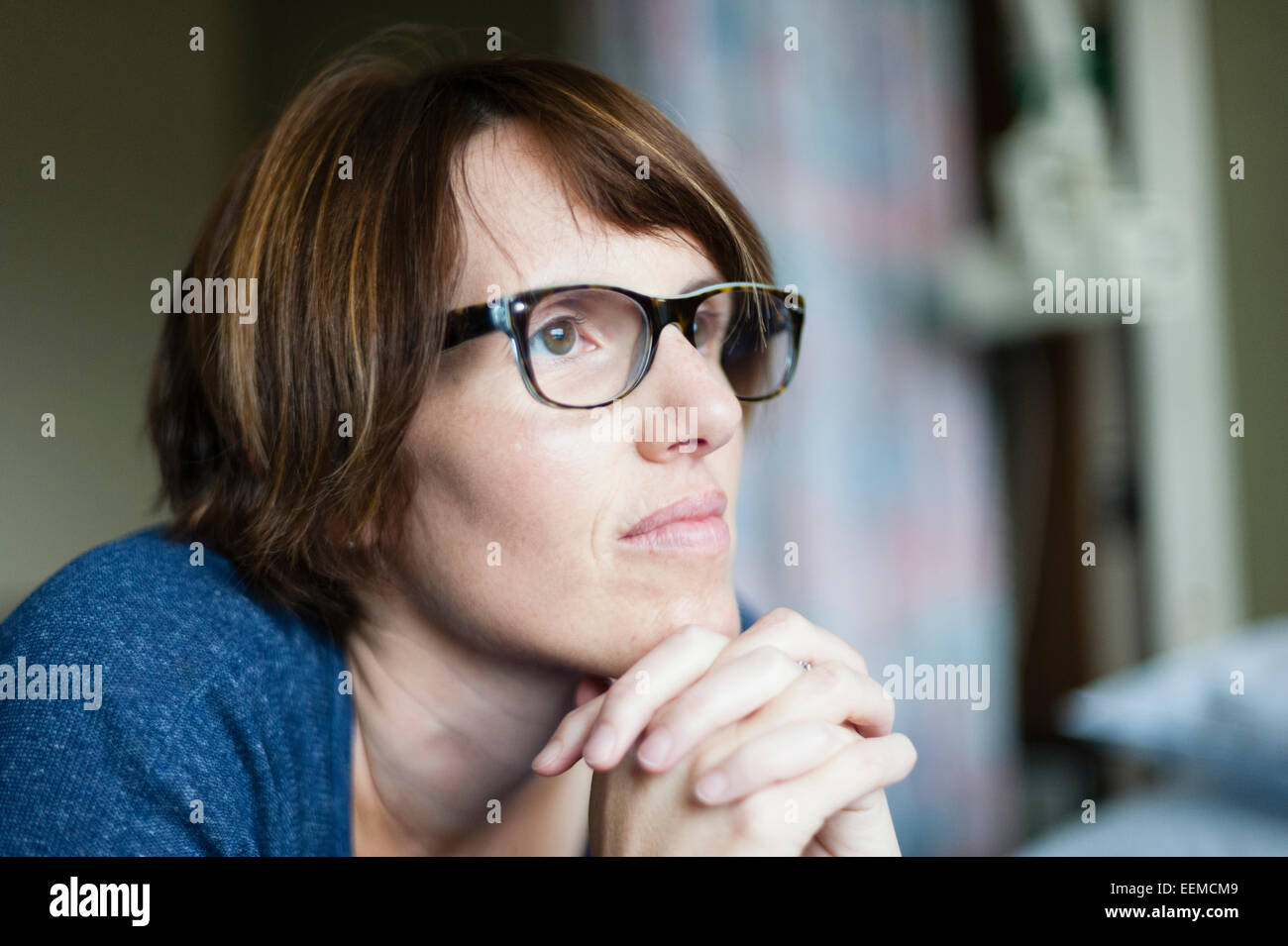 Caucasian woman thinking with hands clasped Stock Photo