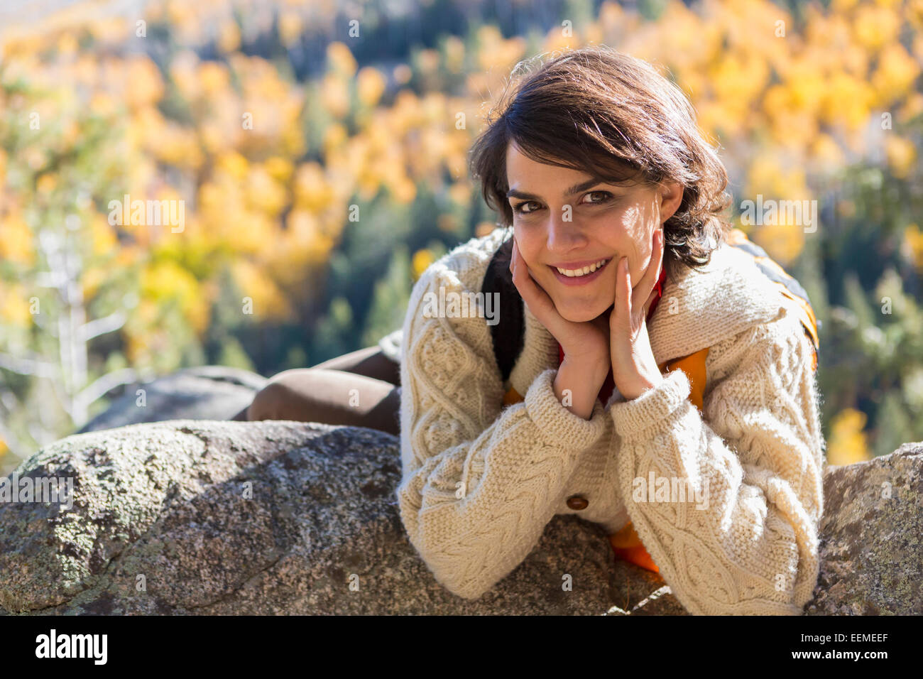 Mixed race woman smiling on rock Stock Photo