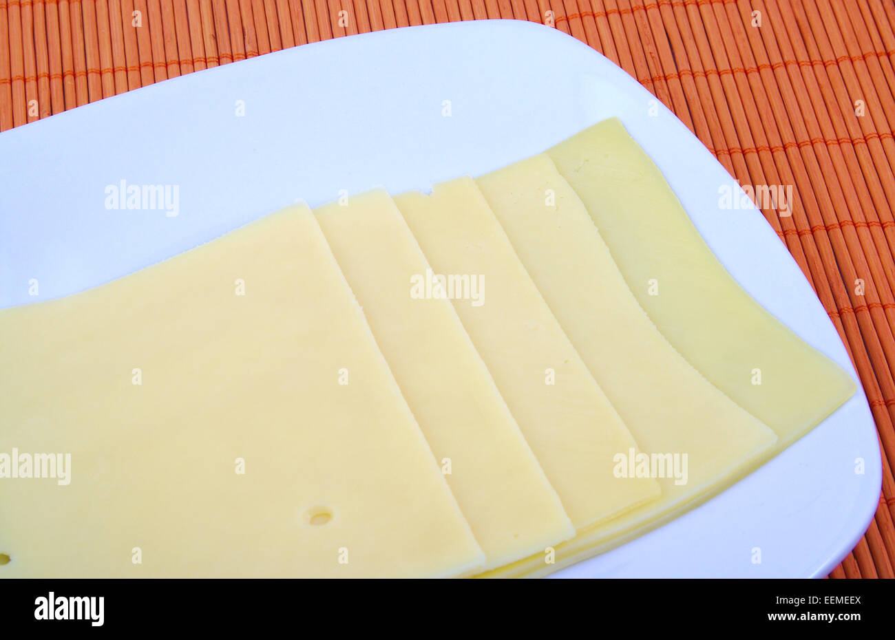 Yellow cheese slices arranged on a white dish Stock Photo