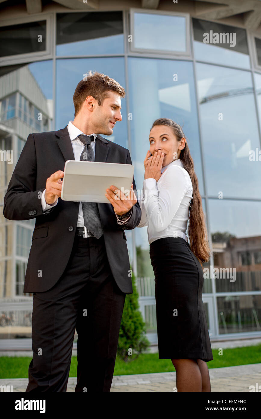 Young Business couple with digital tablet talking and working aganst contemporary building Stock Photo