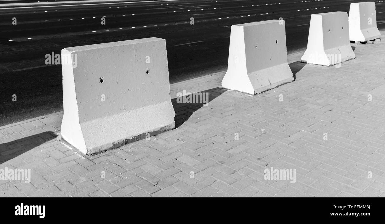 Road barrier. White concrete blocks stand on urban roadside Stock Photo