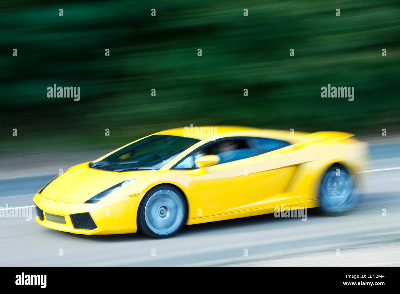 Yellow car driving fast on country road Stock Photo Alamy