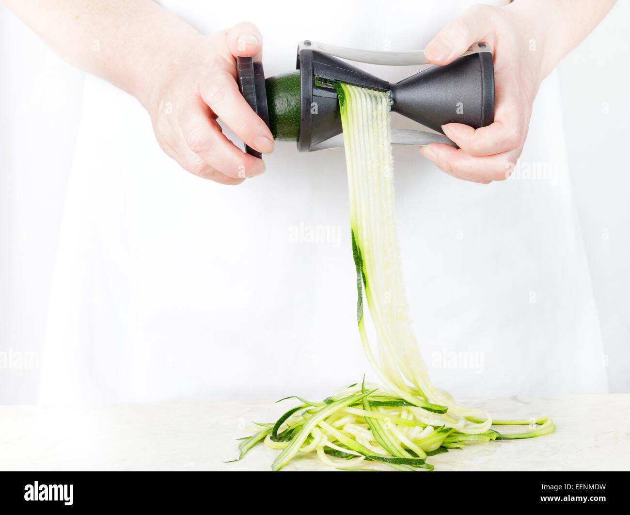 https://c8.alamy.com/comp/EENMDW/using-a-vegetable-spiral-maker-to-make-courgette-zucchini-noodles-EENMDW.jpg
