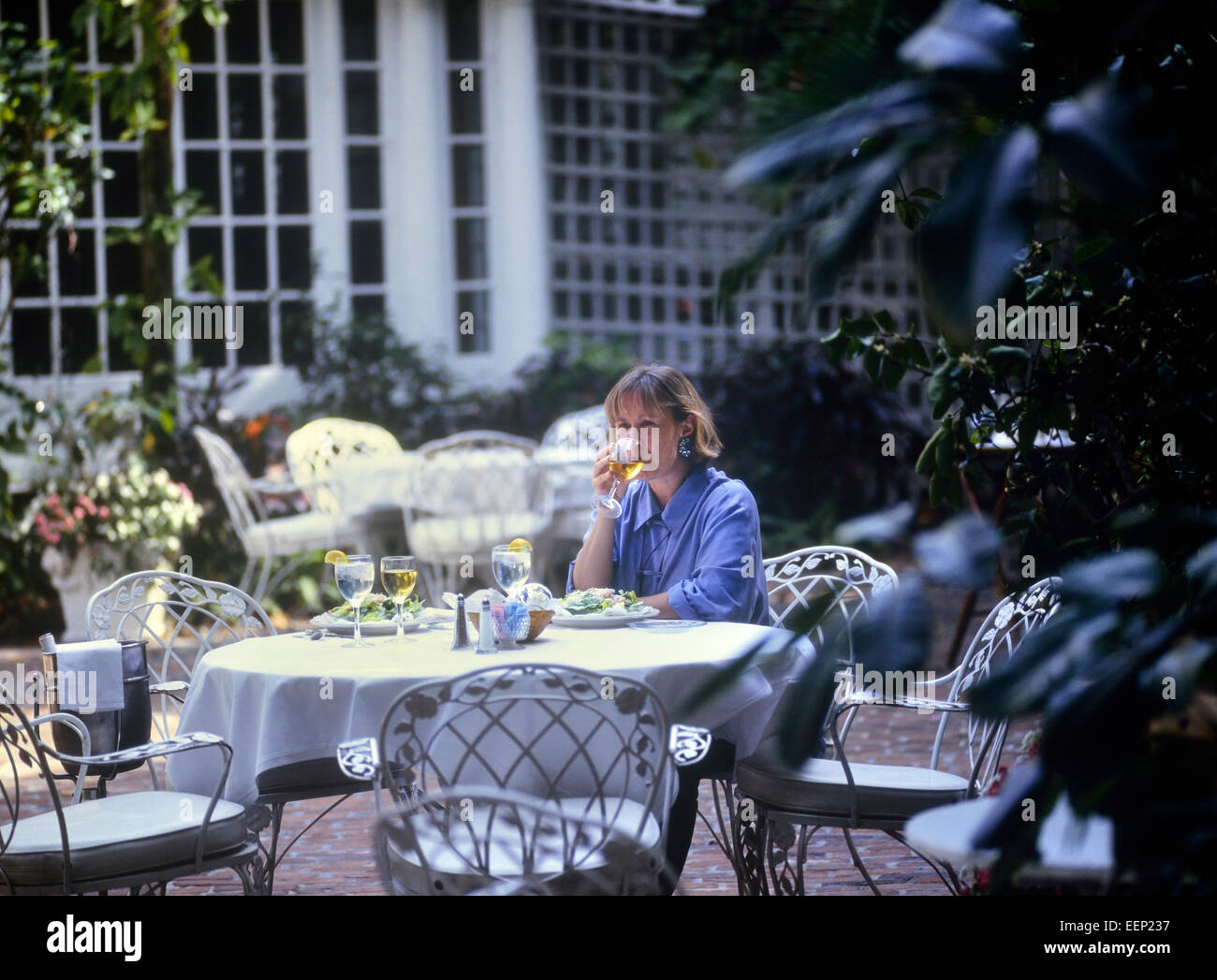 Woman having lunch in a restaurant garden courtyard. The Veranda, Fort Myers. Florida. USA Stock Photo
