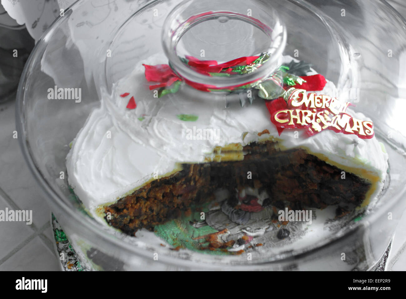 Part eaten rich fruit Christmas cake under glass dome Stock Photo