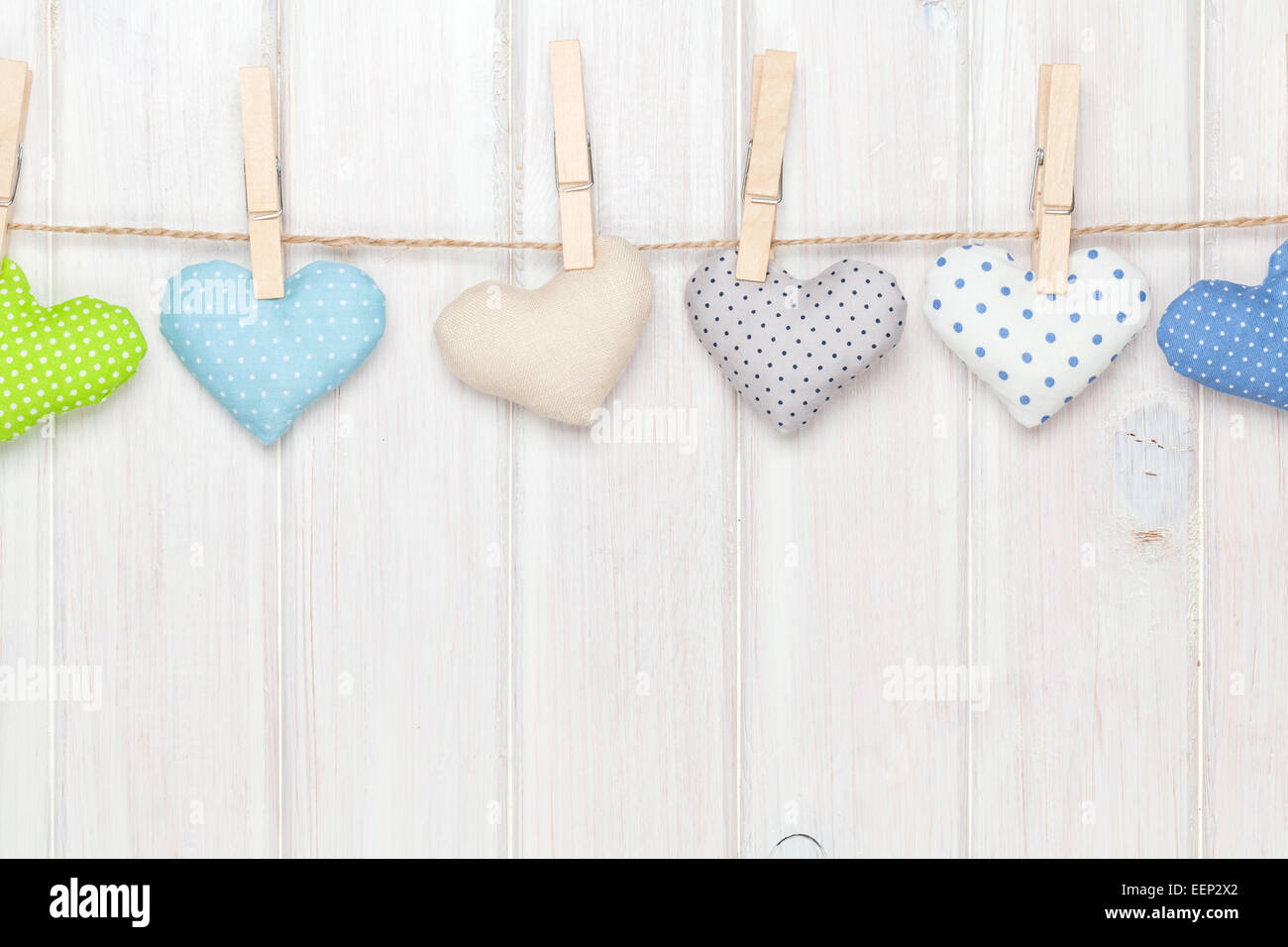 Valentines day toy hearts hanging on rope over white wooden background ...