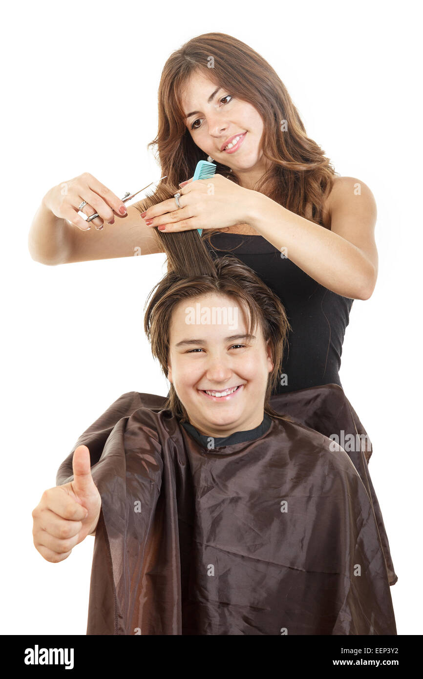 cute young male chubby child kid or boy smiling with long hair with thumb up at happy female hairdresser cutting his hair while  Stock Photo