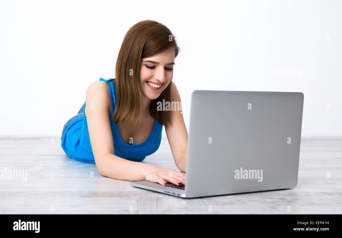 Happy beautiful woman lying on the floor with laptop Stock Photo - Alamy