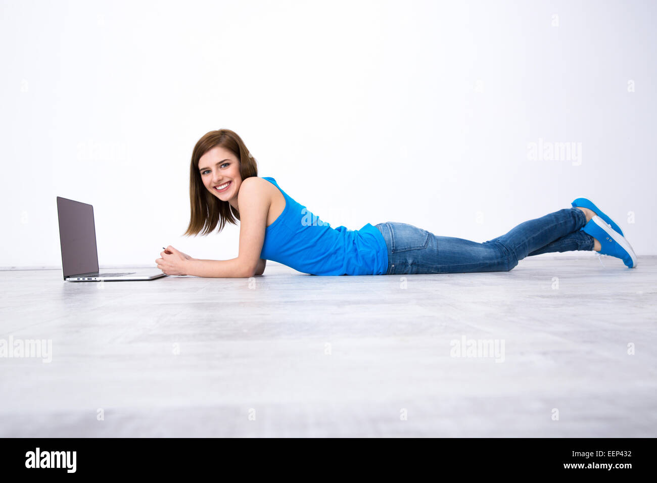 Portrait of a smiling woman lying on the floor with laptop Stock Photo ...