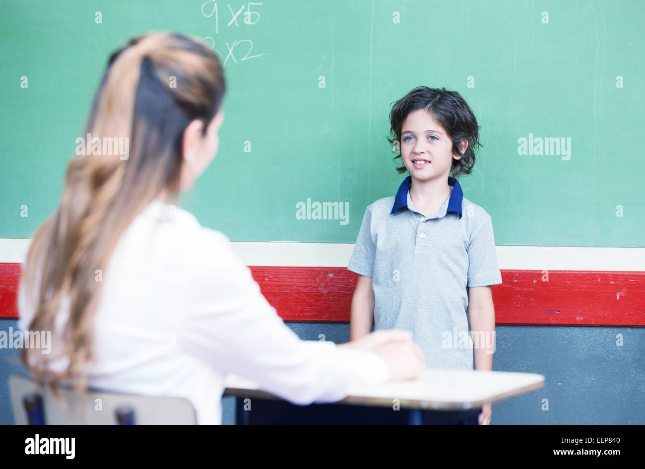 Kid questioned at school in front of chalkboard. Stock Photo