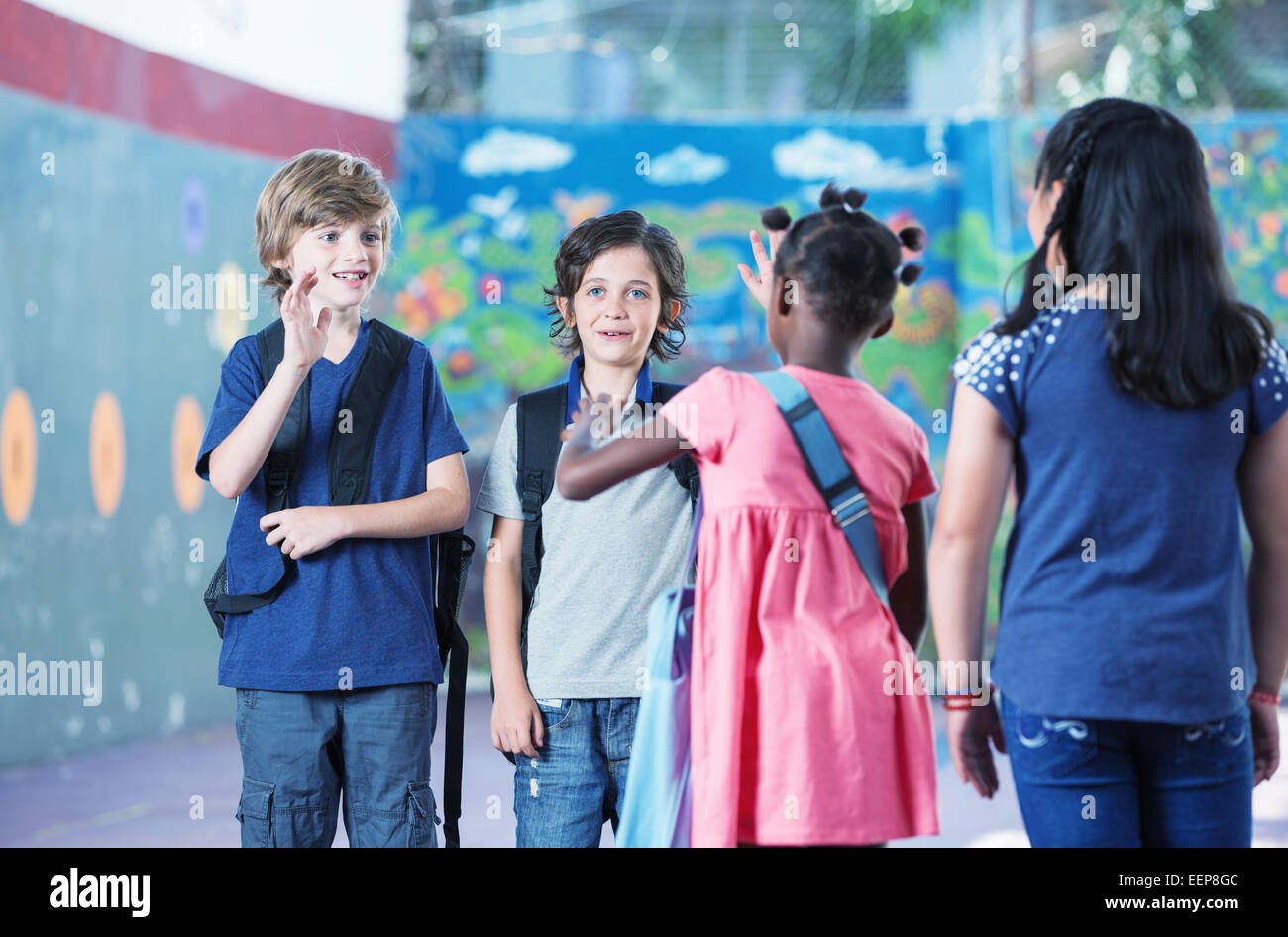 Multi ethnic elementary classroom kids greeting each other in the school yard. Stock Photo