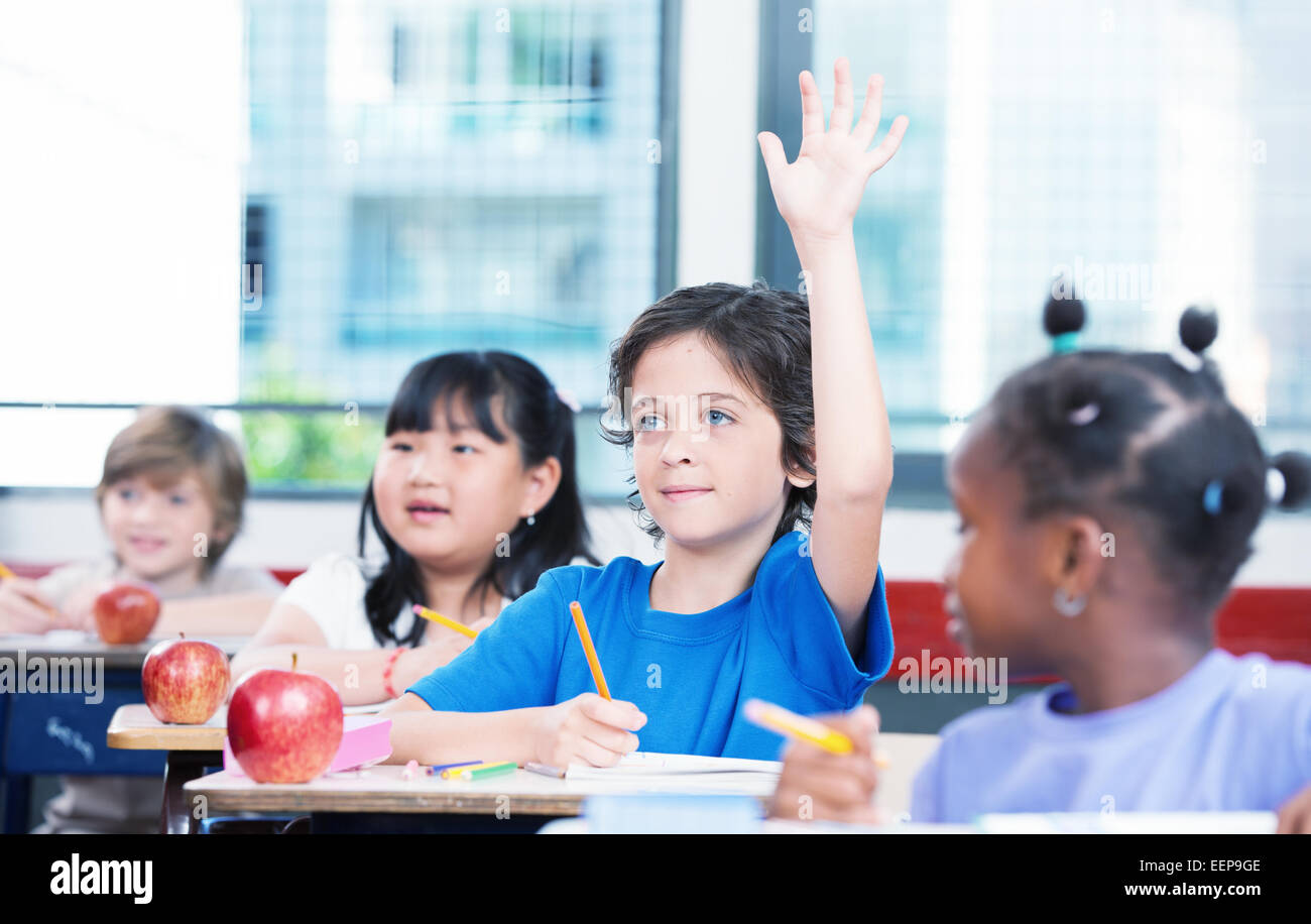 Multiracial classroom primary school. Kid raising his hand ready to answer. Stock Photo