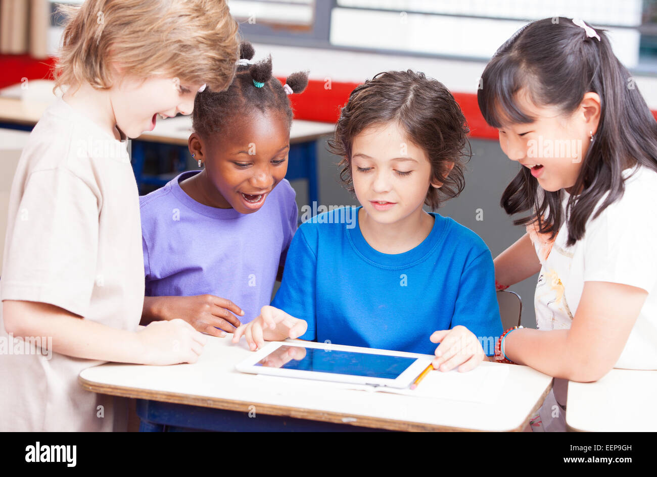 Multi-ethnic classroom playing with tablet. Happy school concept. Stock Photo