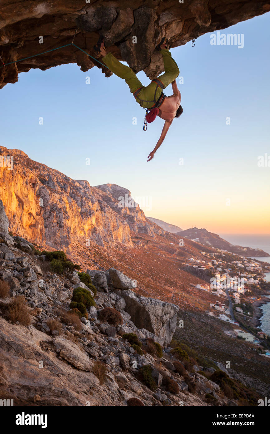 Male climber on overhanging rock against beautiful view of coast below Stock Photo