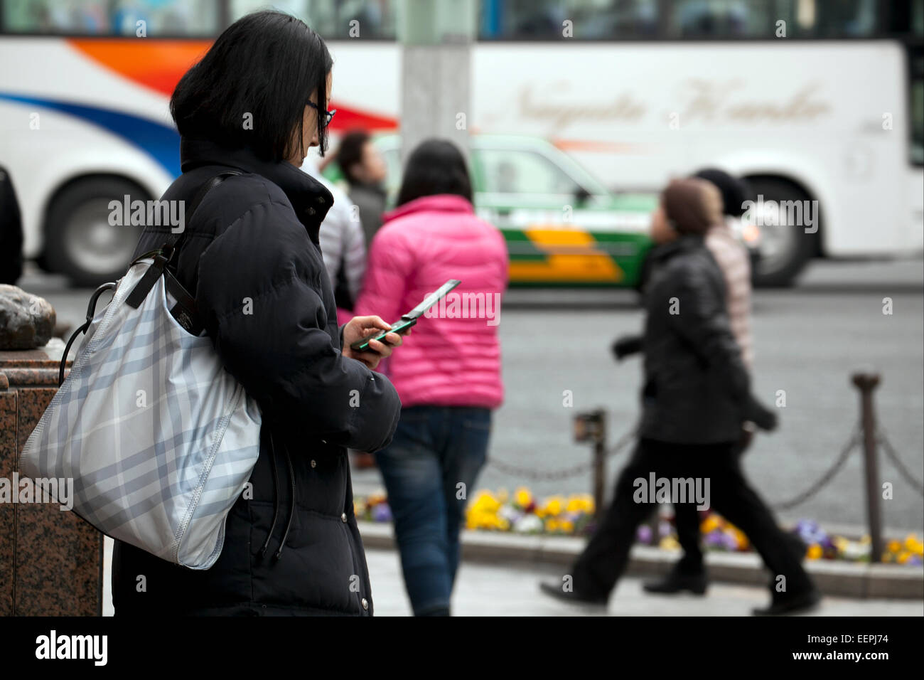 Tokyo, Japan. 17th Feb, 2015. A woman uses a flip-phone on the street in Ginza shopping district on February 17, 2015, Tokyo, Japan. According to data from MM Research Institute Flip-phones sales increased for first time in seven years in Japan in 2014. In Japan flip-phones monthly rates are cheaper in comparison to smartphones which are more expensive than in other countries. Flip-phones sales rose 5.7% in 2014 whilst smartphone sales declined 5.3%. Credit:  Rodrigo Reyes Marin/AFLO/Alamy Live News Stock Photo