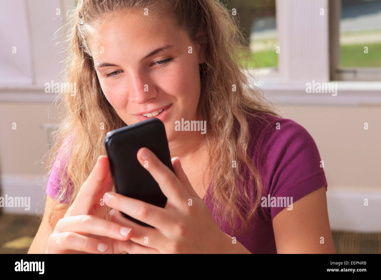 Student with visual impairment using her cell phone in her dorm room Stock Photo