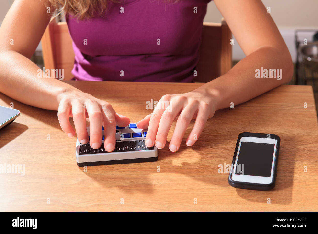 Student with visual impairment using her Braille display in her dorm room Stock Photo