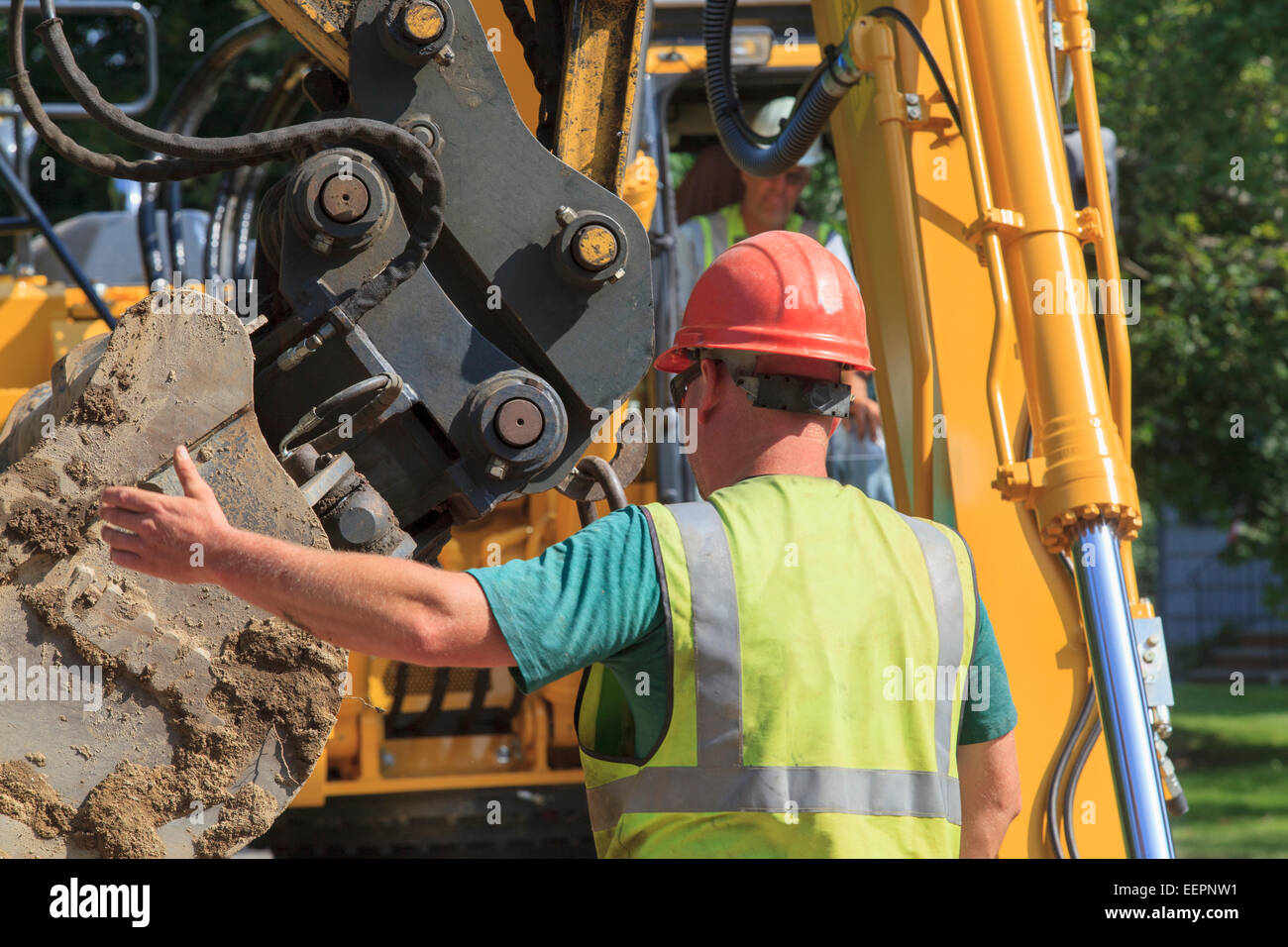 Construction foreman guiding excavator operator Stock Photo