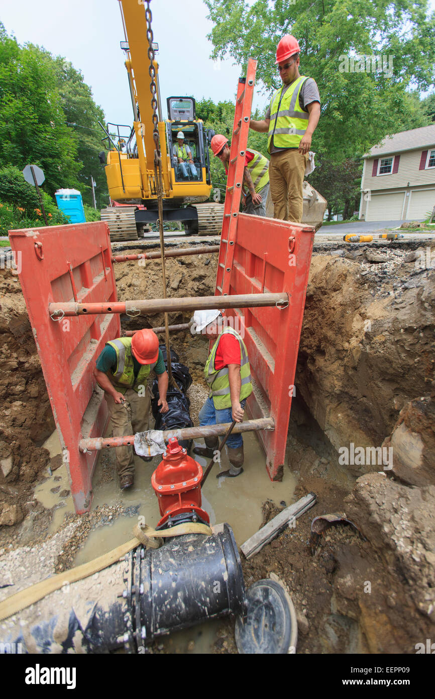 Construction workers working with water main pipe inside shoring Stock Photo