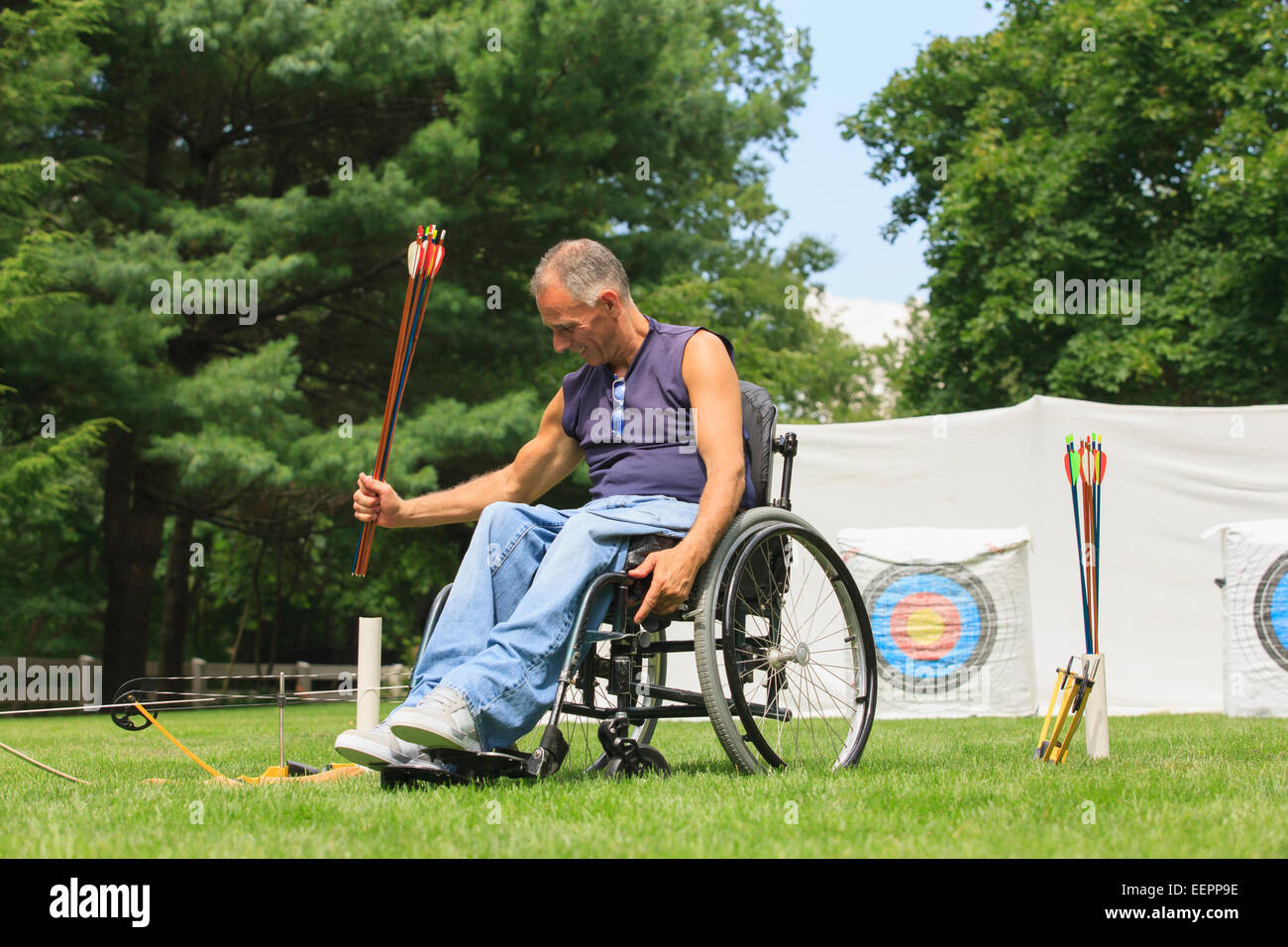 Man with spinal cord injury in wheelchair preparing for archery