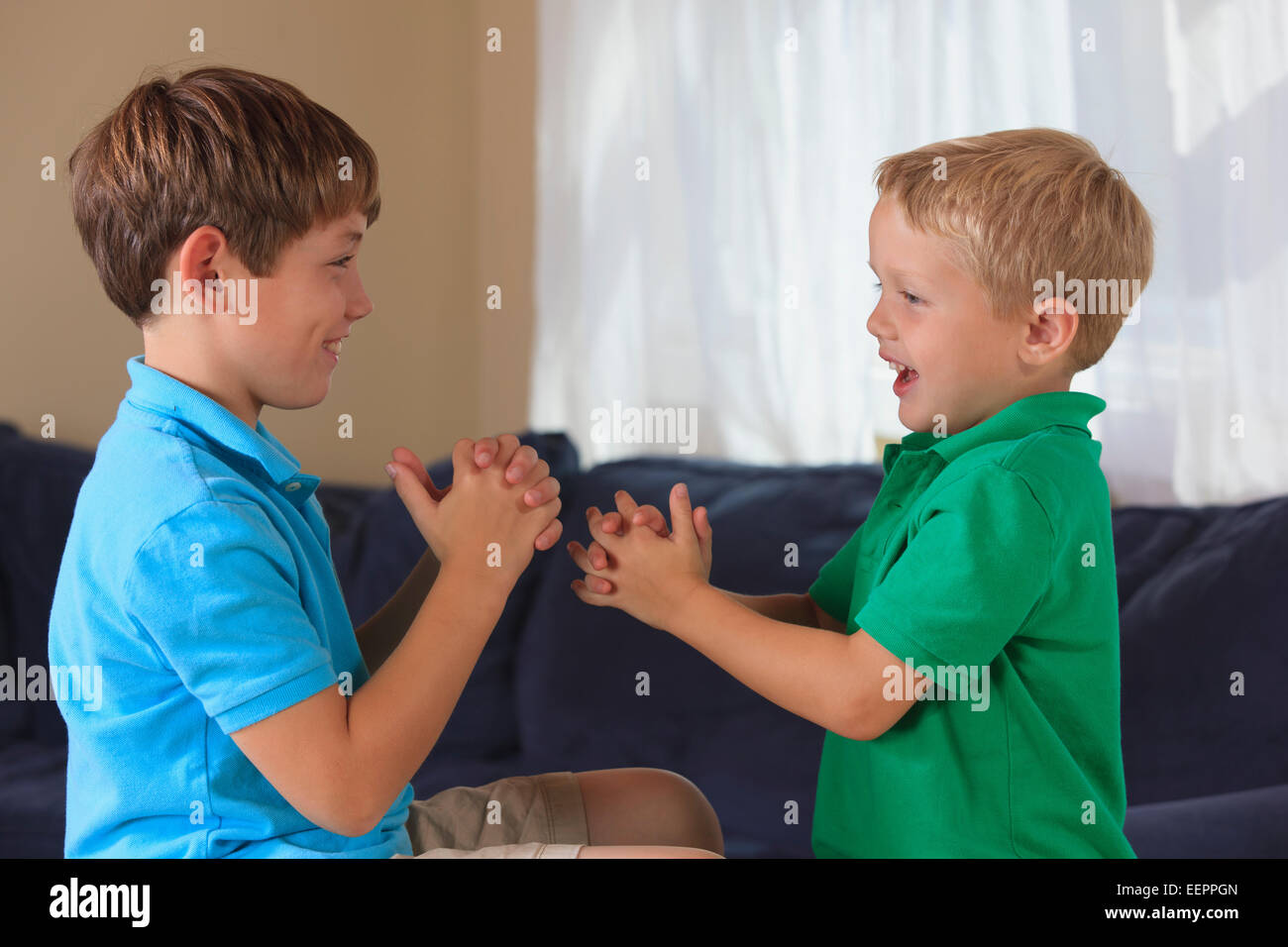 Boys with hearing impairments signing 'wrestling' in American sign language on their couch Stock Photo