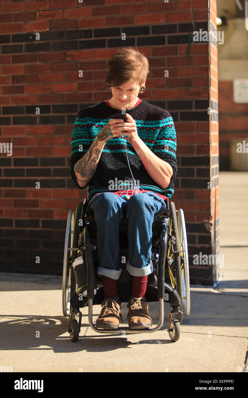 Trendy man with a spinal cord injury in wheelchair taking his text