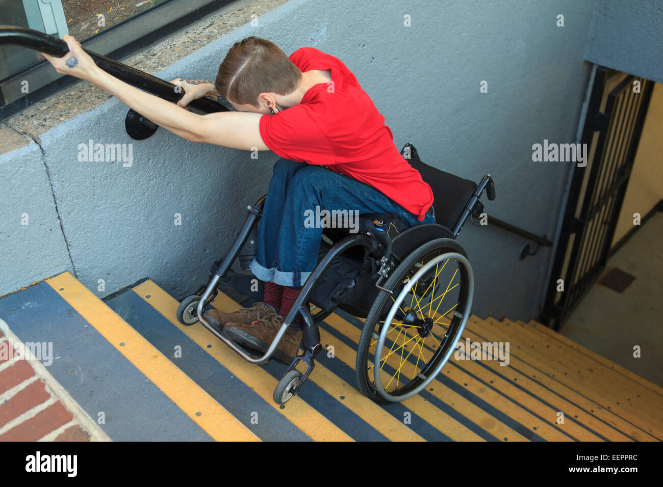 Trendy man with a spinal cord injury in wheelchair going down subway stairs backwards Stock Photo
