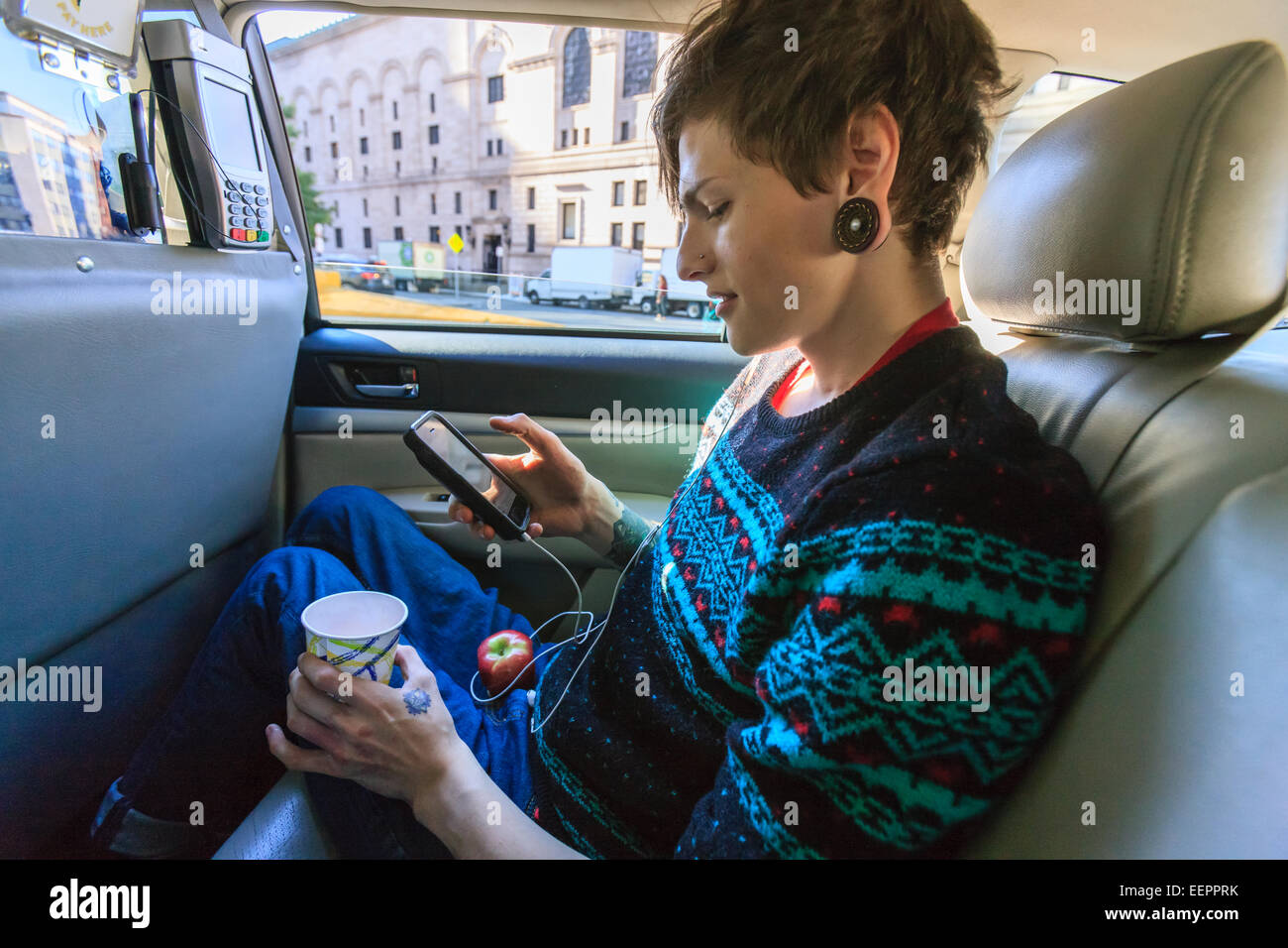 Trendy man with a spinal cord injury in wheelchair inside a taxi cab reading his text messages Stock Photo