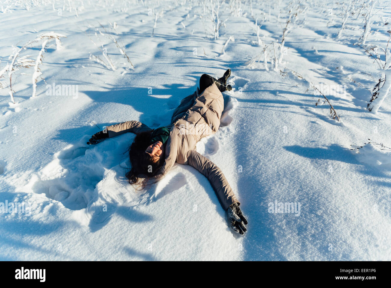 Beautiful brunette girl smiling and lying on the snow Stock Photo