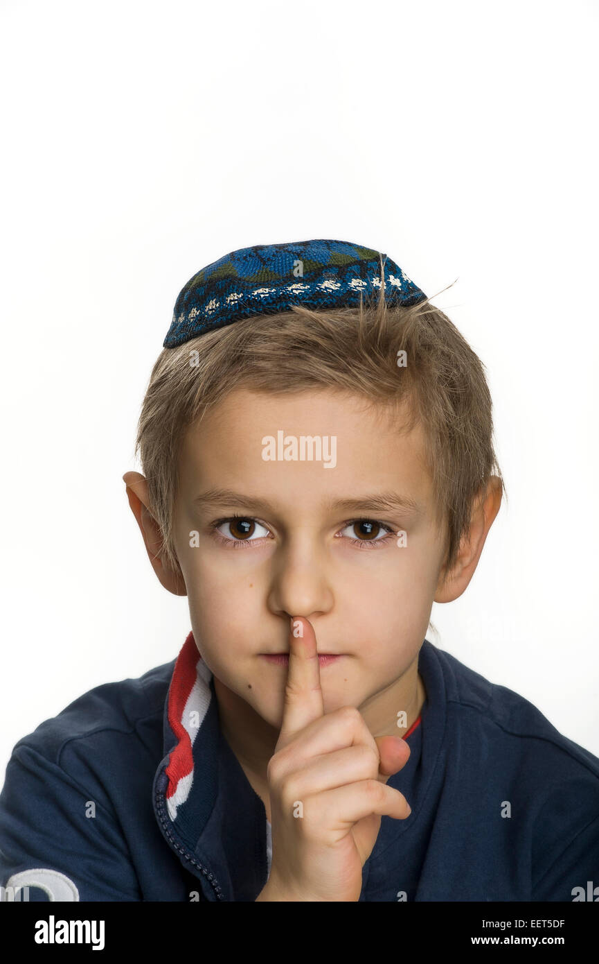 studio portrait of white boy with Jews kipa or yarmulke making gesture be silent Stock Photo