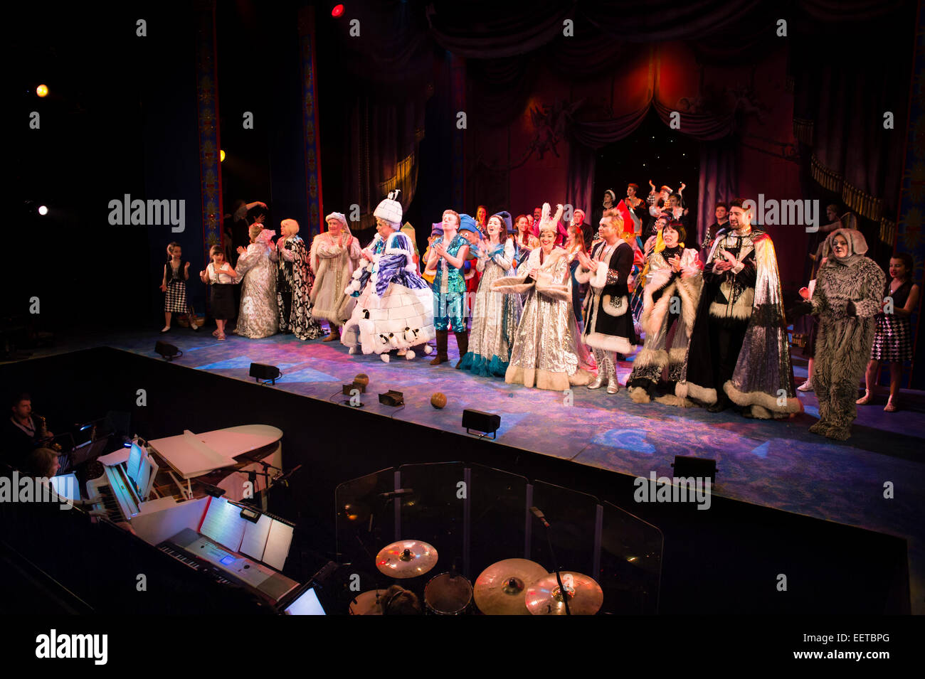 A cast of amateur actors performing in their elaborate costumes on stage  for the finale of "Snow White and the Seven Dwarfs" traditional 'panto'  pantomime, and the band in the orchestra pit