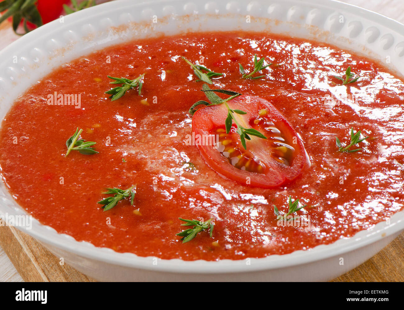 Fresh tomato soup in a white bowl on a wooden table Stock Photo