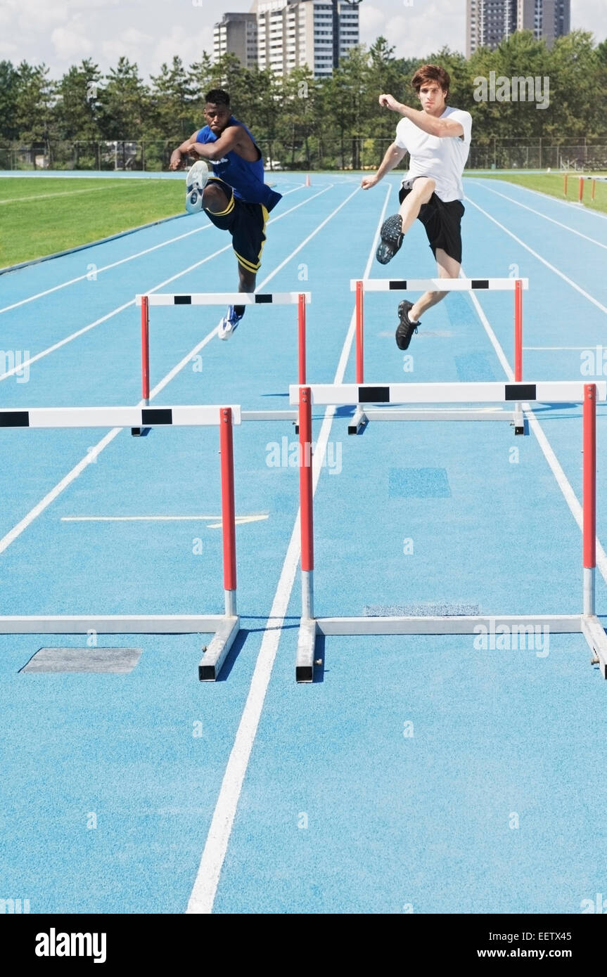 Woman jumping hurdles on a track Stock Photo Alamy