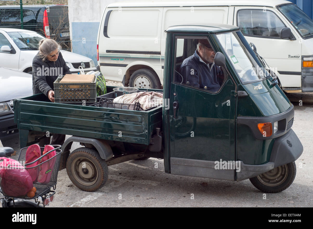 old portuguese woman loading goods into a 3 wheeler truck Stock Photo